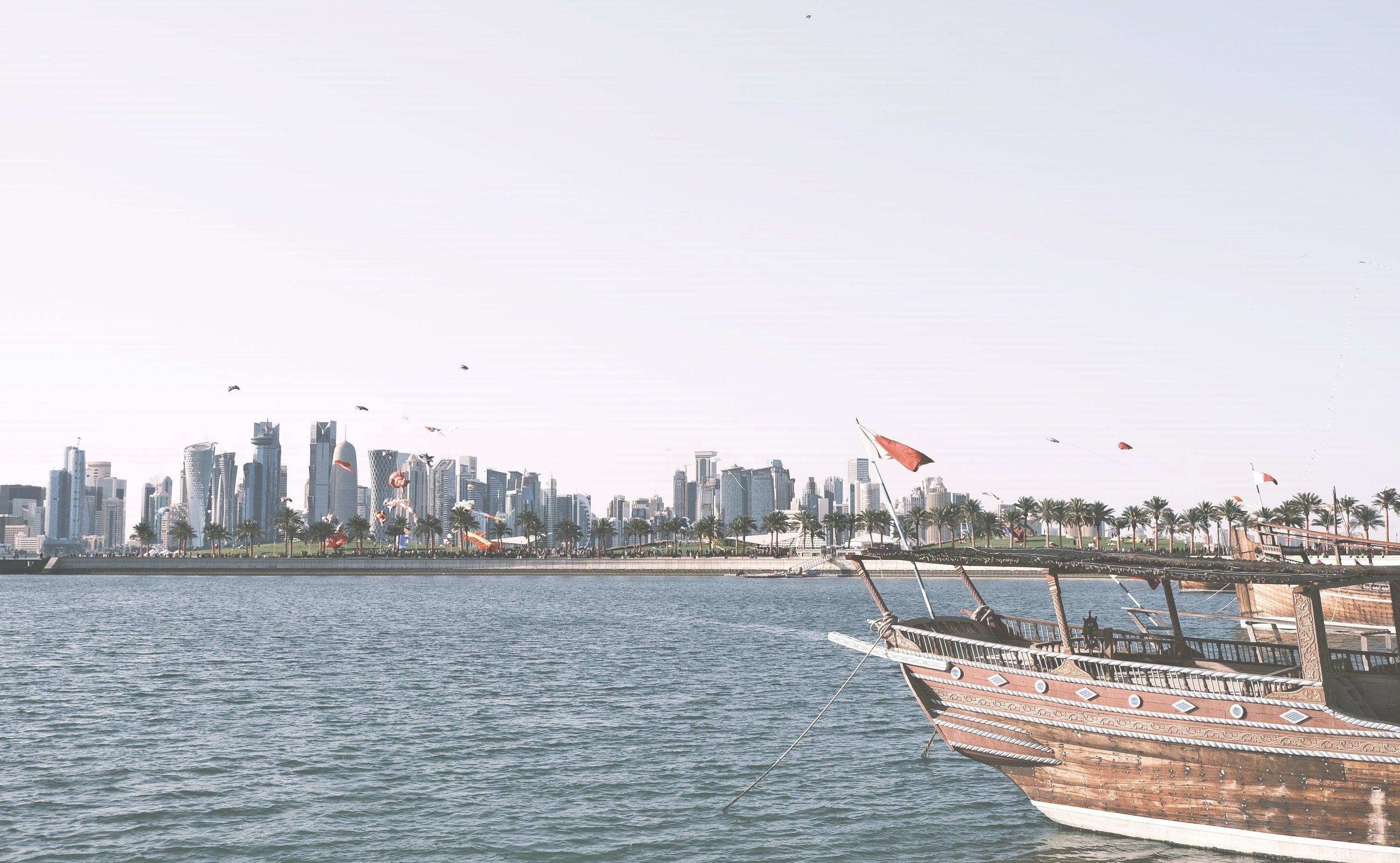 Traditional dhows on Doha Bay at dusk, with the West Bay towers beyond